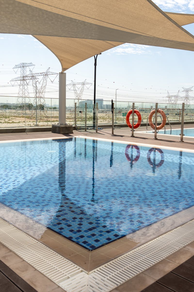 Outdoor swimming pool with sun shade in Dubai, showcasing a pleasant outdoor atmosphere.