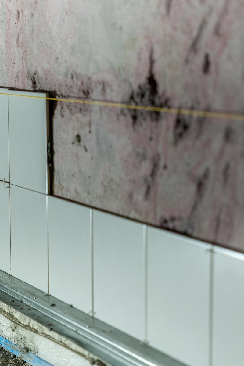 Close-up of partially tiled wall in a construction area, showcasing incomplete renovation work.