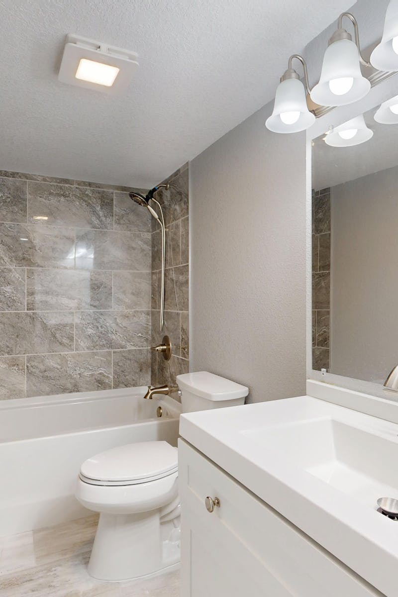Elegant modern bathroom featuring marble tiles and sleek white vanity.